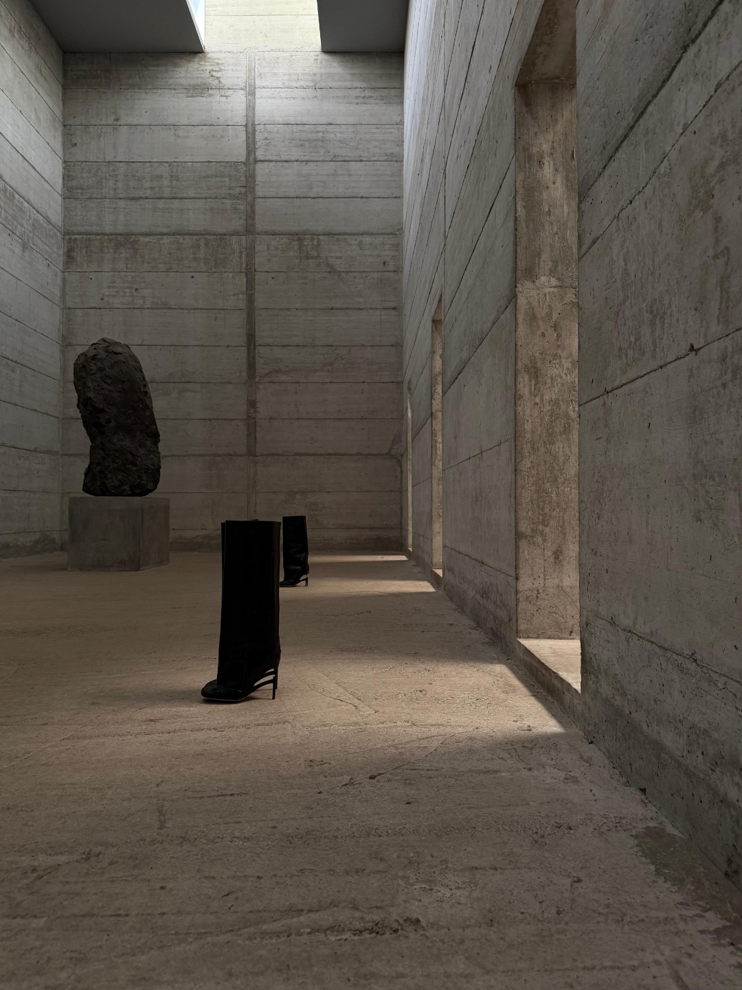 Empty knee-high boots on a chapel floor beside a stone monolith.