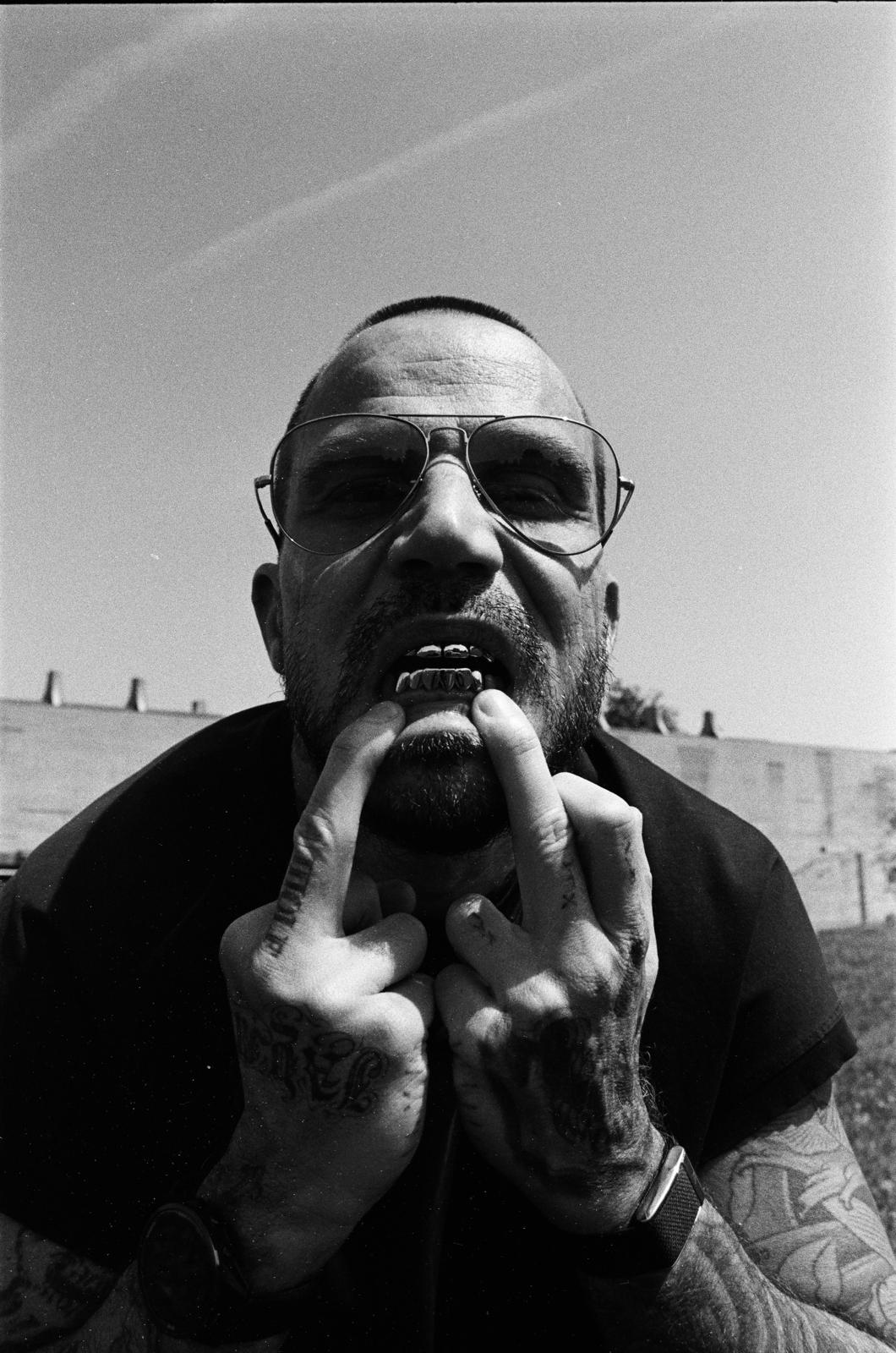 Ben Taverniti — aviators, gold grill, tattooed hands.