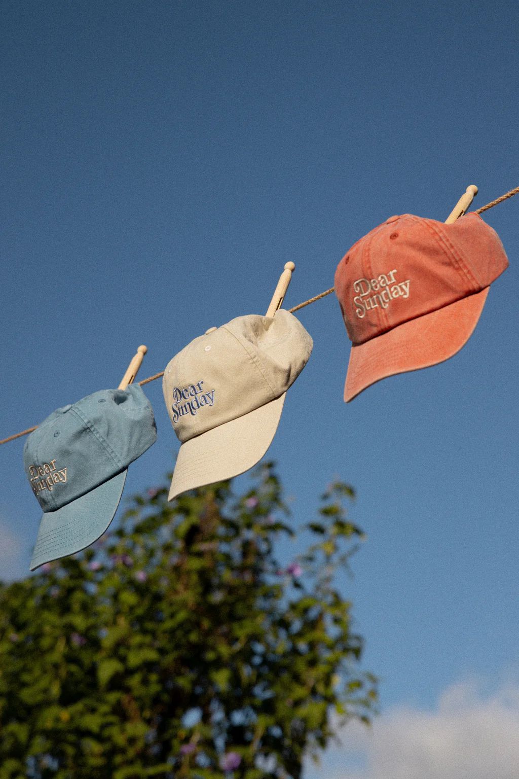 Three caps on clothesline against sky
