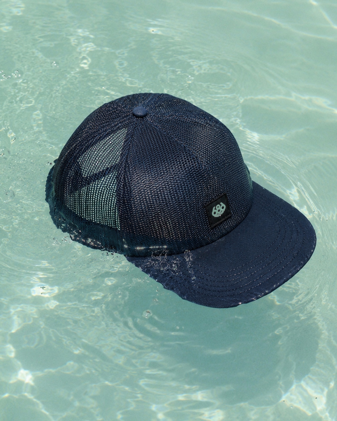 Quick-dry — navy mesh cap floating in pool water